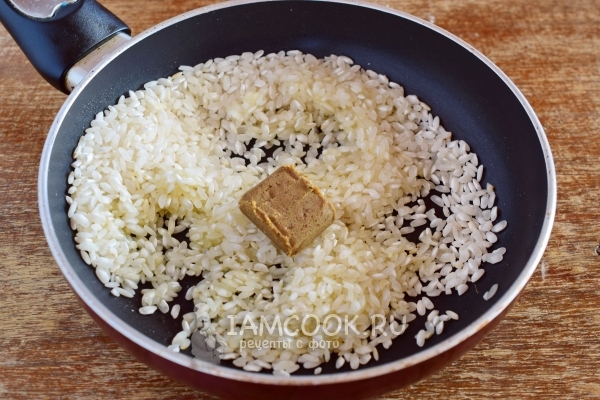 Положить на сковороду рис и бульонный кубик