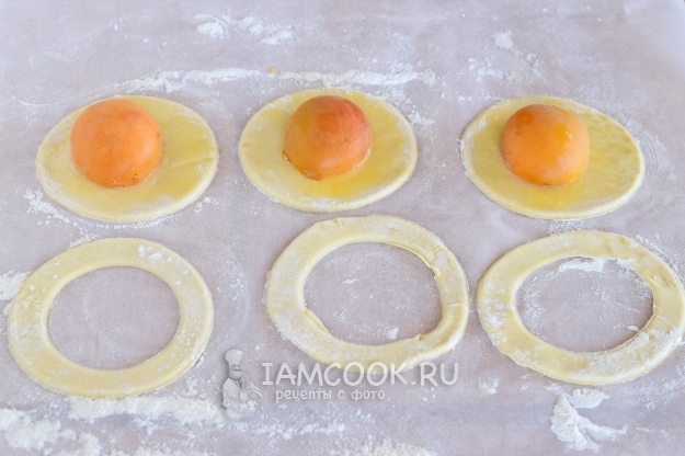 Положить на тесто половинки абрикосов