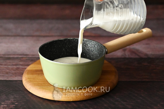 Молоко в ковше на плите, готовится к закипанию