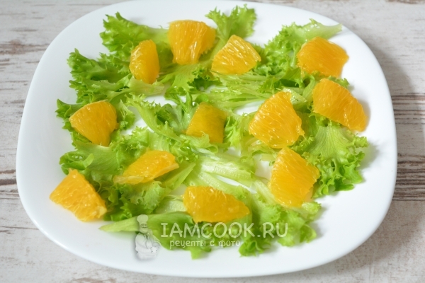 Положить на тарелку листья салата и апельсин